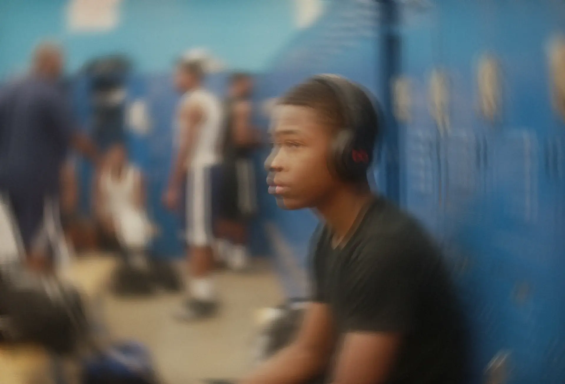 Athlete alone in the locker room before a game, eyes closed, headphones on